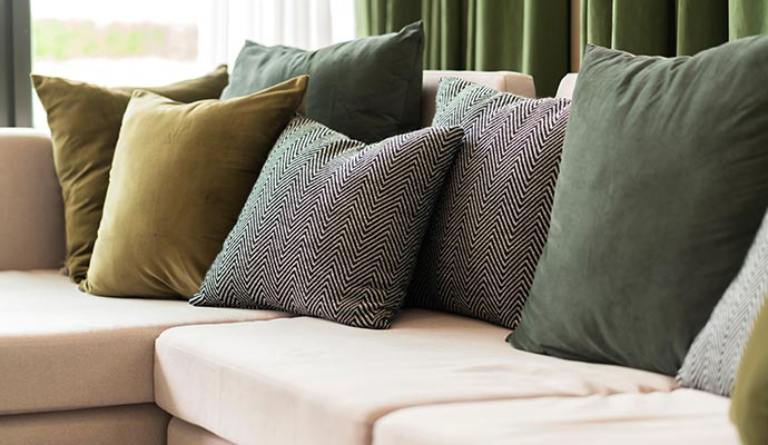 A collection of colorful patterned throw pillows arranged on a gray sofa.