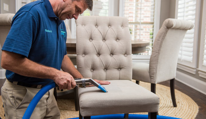 a professional cleaning an upholstered chair