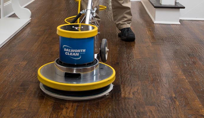 Professional worker cleaning wood floor